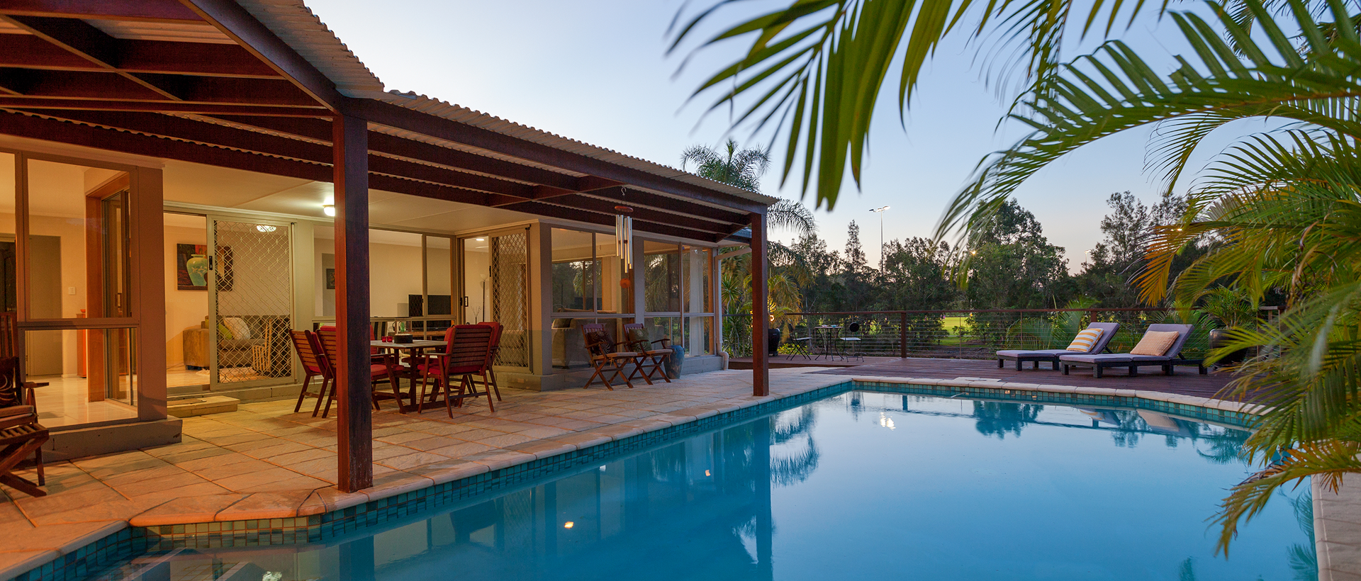 Poolside patio with seating and palm trees.