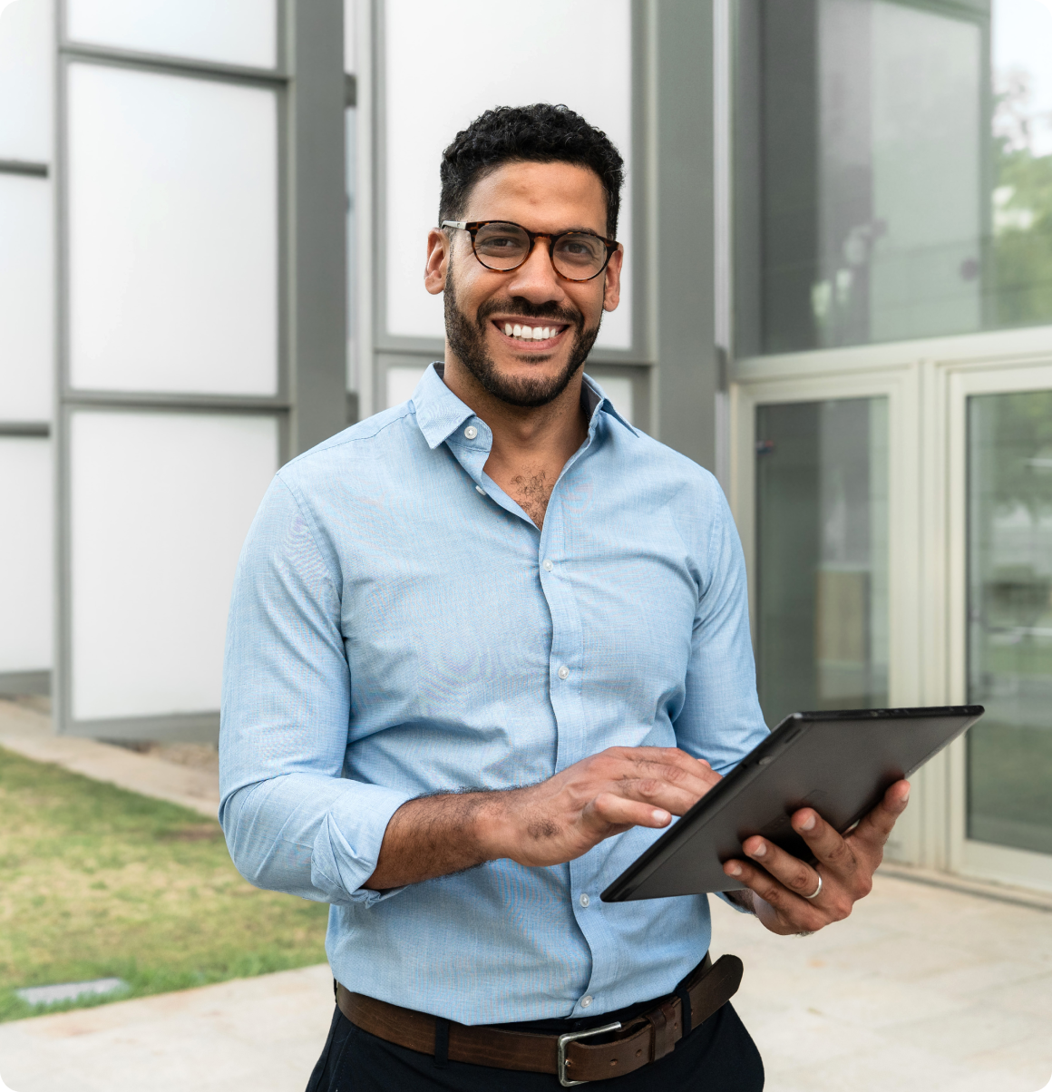 Man smiling while using a tablet outdoors.